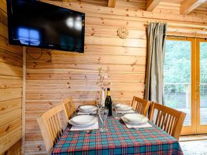 a dining room with a table with chairs and a television at Larch - Uk31134 in Killin