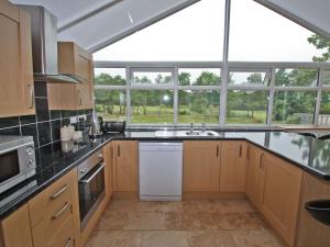 a kitchen with wooden cabinets and a large window at Springfield Court - Lakeview in Bonvilston