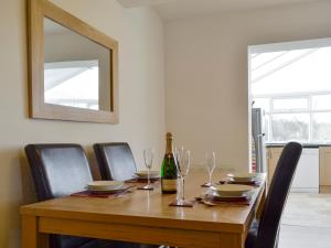 a dining room table with chairs and a bottle of wine at Springfield Court - Lakeview in Bonvilston
