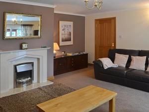 a living room with a black couch and a fireplace at The Willows Red Row in East Chevington