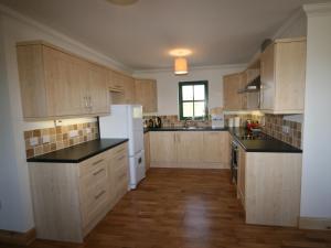 a large kitchen with wooden cabinets and black counter tops at Taigh Uaine in Culkein