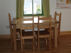 a wooden dining room table and chairs with a window at Taigh Uaine in Culkein