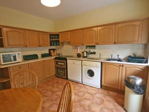 a kitchen with wooden cabinets and a washing machine at Humbleton Falls in Wooler