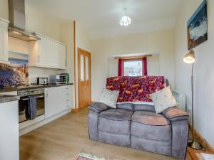 a living room with a couch and a kitchen at The Stable Mey in Scarfskerry