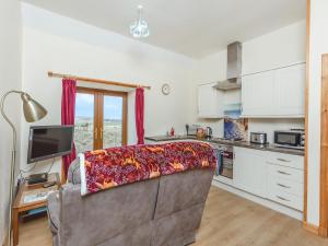 a living room with a couch and a kitchen at The Stable Mey in Scarfskerry