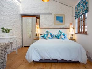 a bedroom with a white bed with blue pillows at Mill Balcony in Ashsprington +3 photos