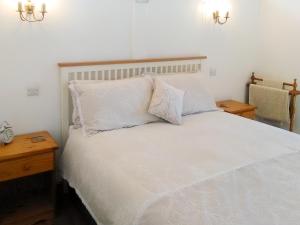 a bedroom with a white bed with two pillows at Tawmans in Kilmuir +7 photos