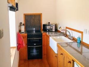 a kitchen with a black stove top oven next to a sink at Tawmans in Kilmuir