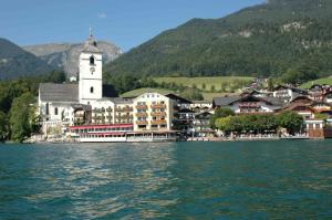 a town on the shore of a lake with a clock tower at Hotel Zimmerbräu in St. Wolfgang