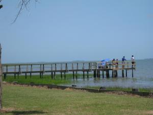 personas de pie en un muelle cerca del agua en Virginia Landing Camping Resort Cabin 17, en Quinby