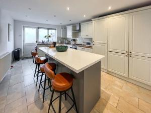 a kitchen with white cabinets and a island with bar stools at Return Again in Beaumaris
