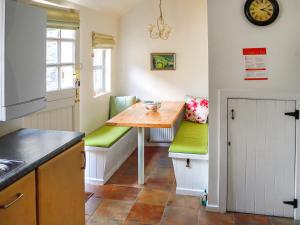 a kitchen with a small table and green chairs at Newbiggin Cottage in Richmond