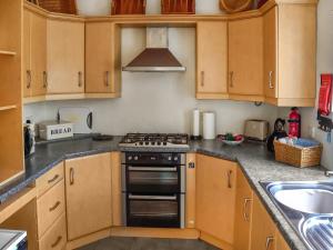 a kitchen with wooden cabinets and a stove top oven at Newbiggin Cottage in Richmond