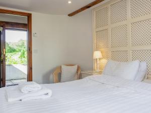 a bedroom with a bed with white sheets and a window at Old Dairy in Chulmleigh +15 photos