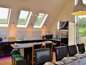 a kitchen with black counters and chairs and windows at Shelduck House in Port na Long