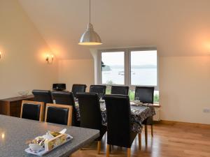 a dining room with a long table and chairs at Shelduck House in Port na Long