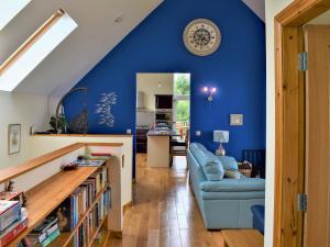 a living room with blue walls and a blue couch at Shelduck House in Port na Long