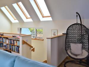 a room with a hanging chair and a book shelf at Shelduck House in Port na Long