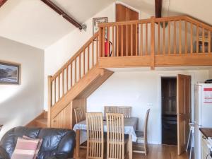 a living room with a staircase and a table and chairs at Yr Hen Weithdy in Llanllechid