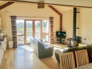 a living room with a couch and a television at Yr Hen Weithdy in Llanllechid