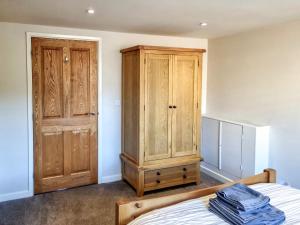 a bedroom with a bed and a wooden cabinet at Yr Hen Weithdy in Llanllechid +17 photos