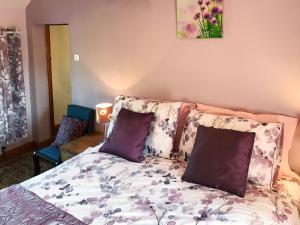 a bedroom with a bed with purple pillows at Bellypig Cottage in Bellerby