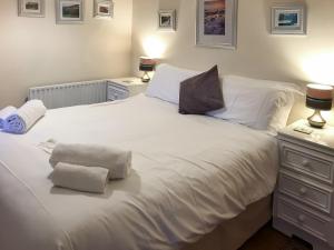 a white bed with two pillows on top of it at Bellypig Cottage in Bellerby +5 photos