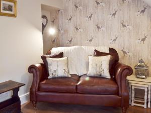 a brown leather couch in a living room with a wallpaper at Mill Race Cottage in Bakewell