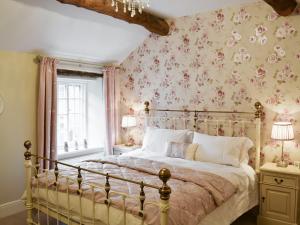 a bedroom with a bed with pink floral wallpaper at Mill Race Cottage in Bakewell