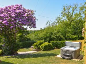 a grill in the yard next to a tree with purple flowers at Seaview Cottage - Uk44707 in Amroth
