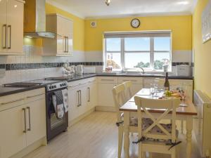 a kitchen with yellow walls and a table with chairs at Seaview Cottage - Uk44707 in Amroth