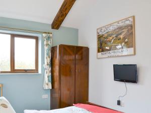 a bedroom with a tv and a wooden cabinet at Shepherdskirk in Kyloe