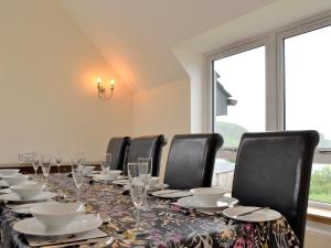 a long table with black chairs and plates and glasses at Shelduck House in Port na Long +12 photos