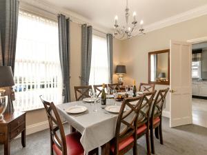 a dining room with a table and chairs and windows at Wold House Cottage in Nafferton