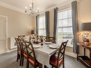 a dining room with a table and chairs and windows at Wold House Cottage in Nafferton