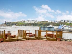 a wooden fence with benches in front of the water at Dorn Rock View - Uk33918 in Portpatrick