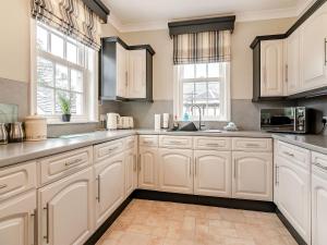 a white kitchen with white cabinets and windows at Wold House Cottage in Nafferton +22 photos