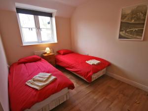 two beds in a room with red sheets and a window at New Bakery in Glanton +5 photos