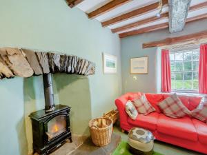 a living room with a red couch and a fireplace at Thwaite Bridge Houseconiston in Coniston