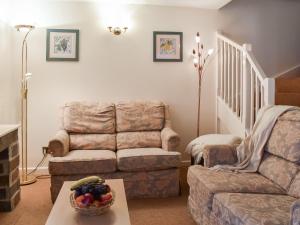 a living room with a couch and a bowl of fruit on a table at Cowshed - Uk49024 in Liskeard