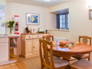 a kitchen and dining room with a wooden table and chairs at Cowshed - Uk49024 in Liskeard