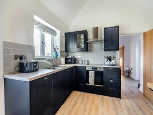 a kitchen with black cabinets and a sink at The Cowshed - Uk37349 in Hockerton