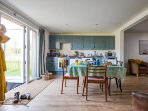a kitchen with green cabinets and a table and chairs at Bueno - Ukc4682 in Clynnog-fawr