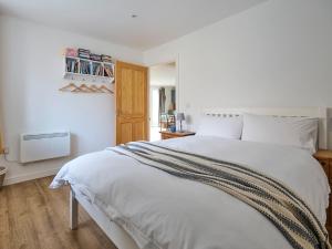 a bedroom with a white bed with a wooden floor at Bueno - Ukc4682 in Clynnog-fawr +5 photos