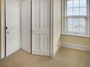 a room with white closet doors and a window at The Farmhouse - Uk49068 in Liskeard +3 photos