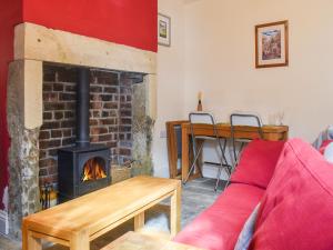 a living room with a fireplace and a red couch at Limestone Cottage in Hebden Bridge