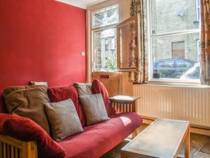 a living room with a red couch and a table at Limestone Cottage in Hebden Bridge