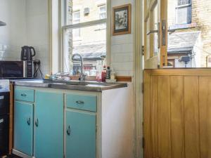 a kitchen with blue cabinets and a sink and a window at Limestone Cottage in Hebden Bridge +6 photos
