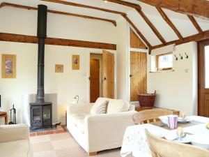 a living room with a white couch and a wood stove at The Dairy At Copper Beeches in Petersfield