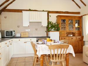 a kitchen with a table and chairs and a kitchen with white cabinets at The Dairy At Copper Beeches in Petersfield